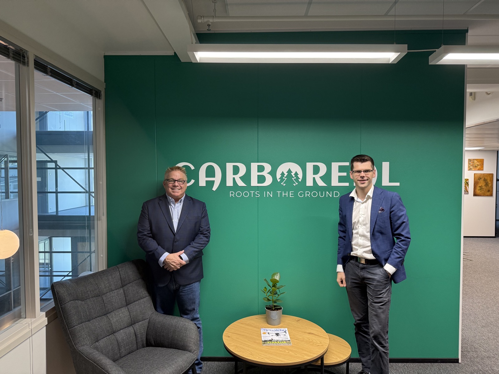 Steve Bender and Taavi Havre at the Carboreal office in front of the Carboreal Roots in the Ground sign